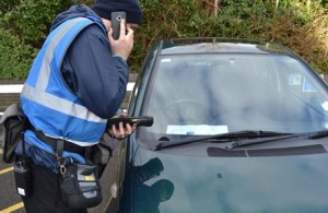 Traffic warden checks a car with a blue badge parked in a disabled bay