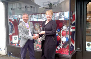 Photo of Cllr Paul Holbrook presenting Best Dressed Platinum Jubilee Window competition winner R. Butler & Sons Funeral Directors with cup award