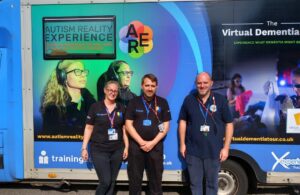 Photo of Deputy Youth Service Manager Joel Cottingham with training staff standing next to the Autism Reality Experience Bus - 26 September 2023