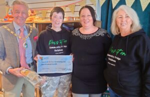 Photo of the mayor Cllr Paul Holbrook presenting a grant cheque to Pass It On (In Your community) CIC volunteers
